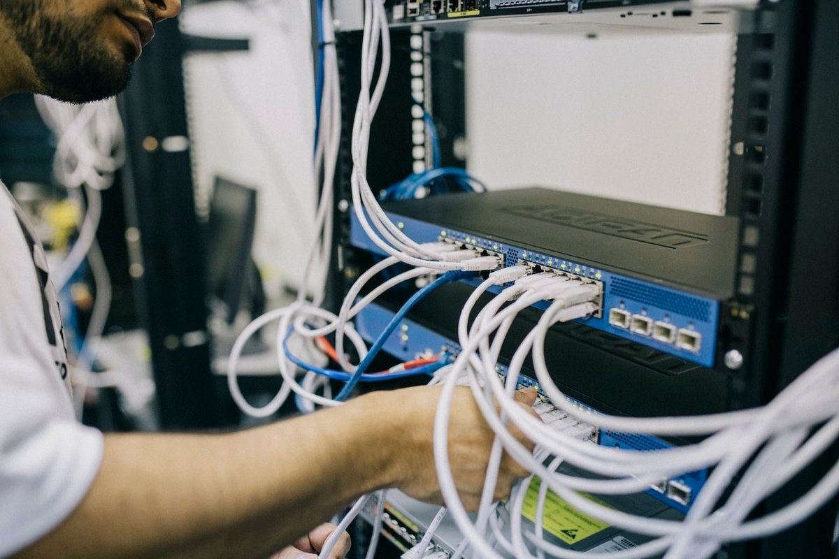 IT technician connecting network cables in a server rack